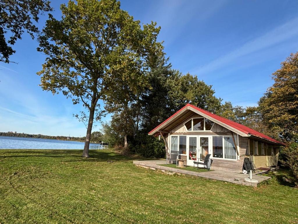 a small cabin on a dock next to a lake at Vakantiehuis - De Smidse in Haren