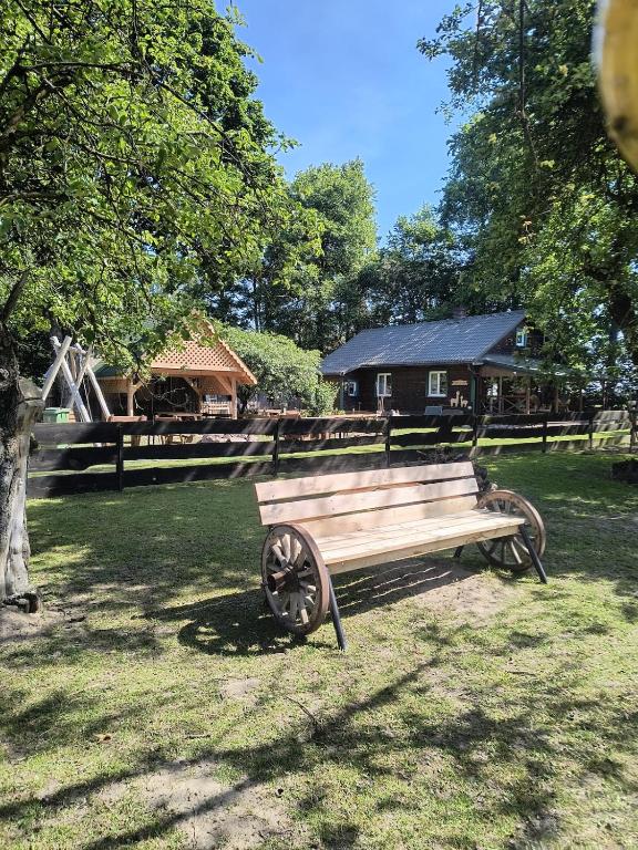 a park bench sitting in the grass in front of a house at Gospodarstwo agroturystyczne alpaki Pituchówka in Łoknica