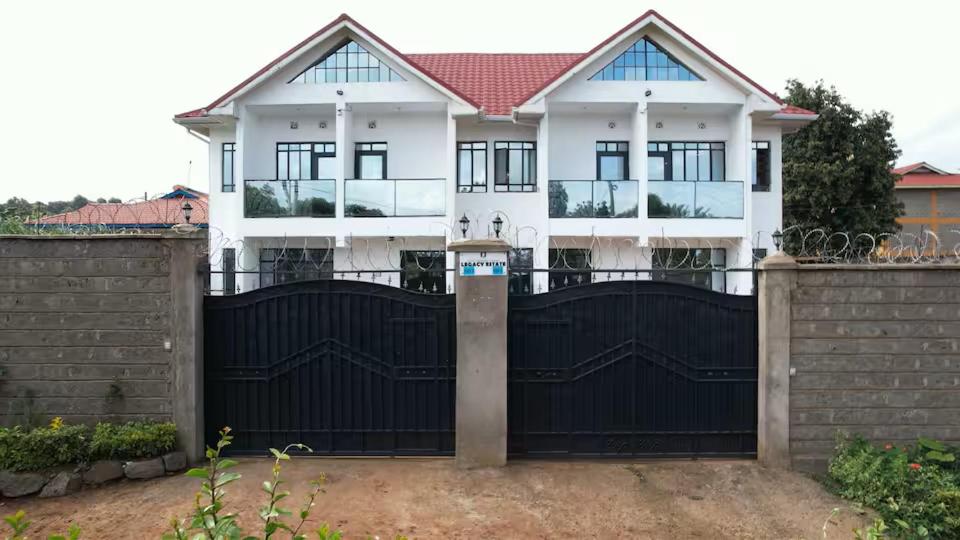 a large white house with a black gate at Legacy by Fralec in Nyeri