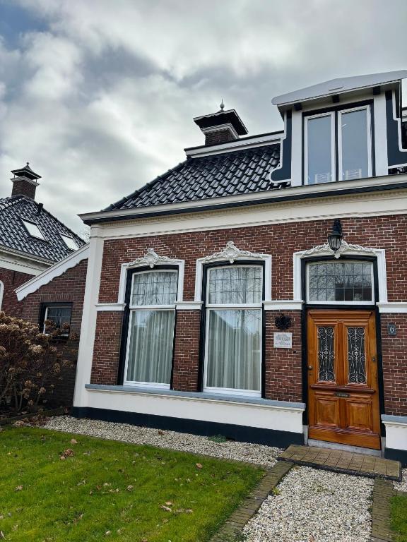 a red brick house with a brown door at B&B de Trochset in Balk