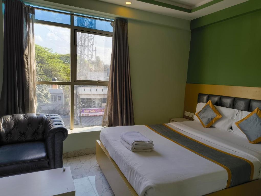 a bedroom with a bed and a chair and a window at Hotel Cozzy Inn in Bangalore
