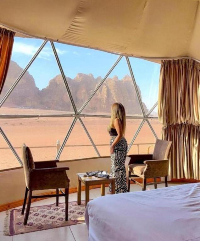 a little girl standing in a room with a large window at RUM iSLAND bubble LUXURU CAMP in Wadi Rum