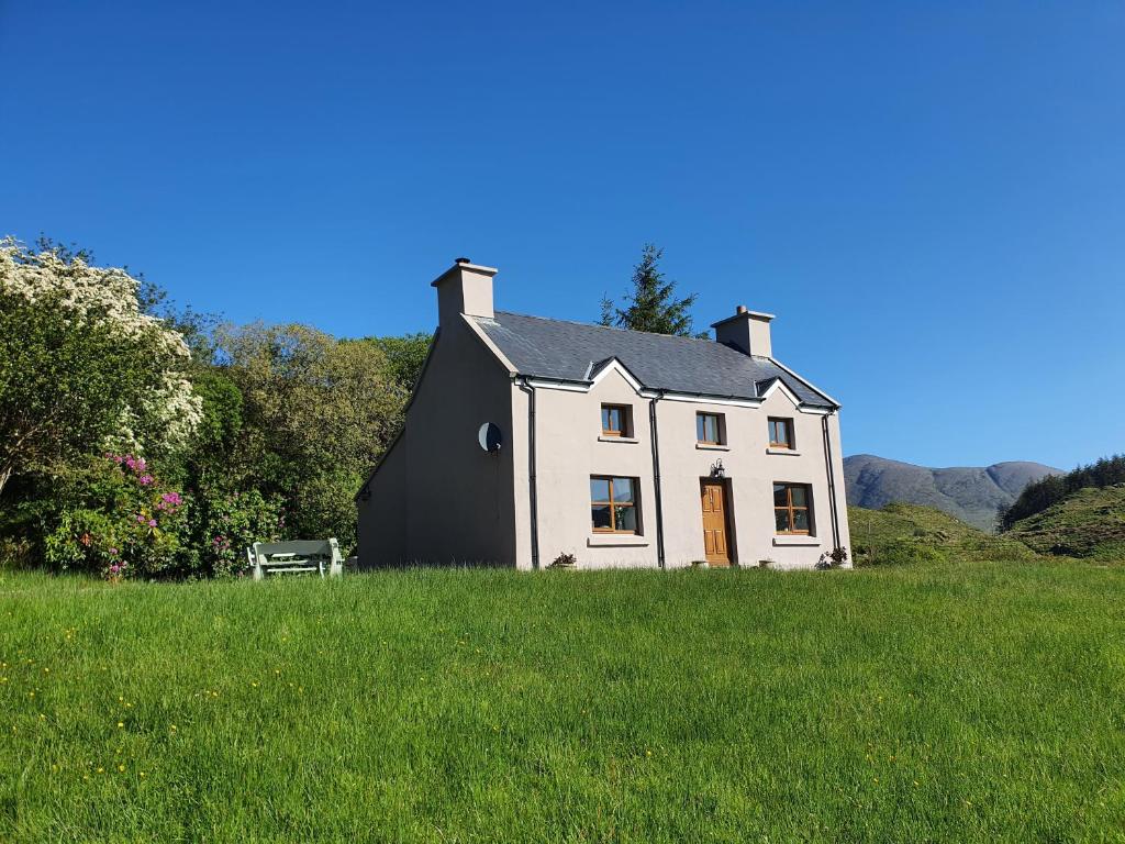 a white house in a field of green grass at An Cnocan in Sneem