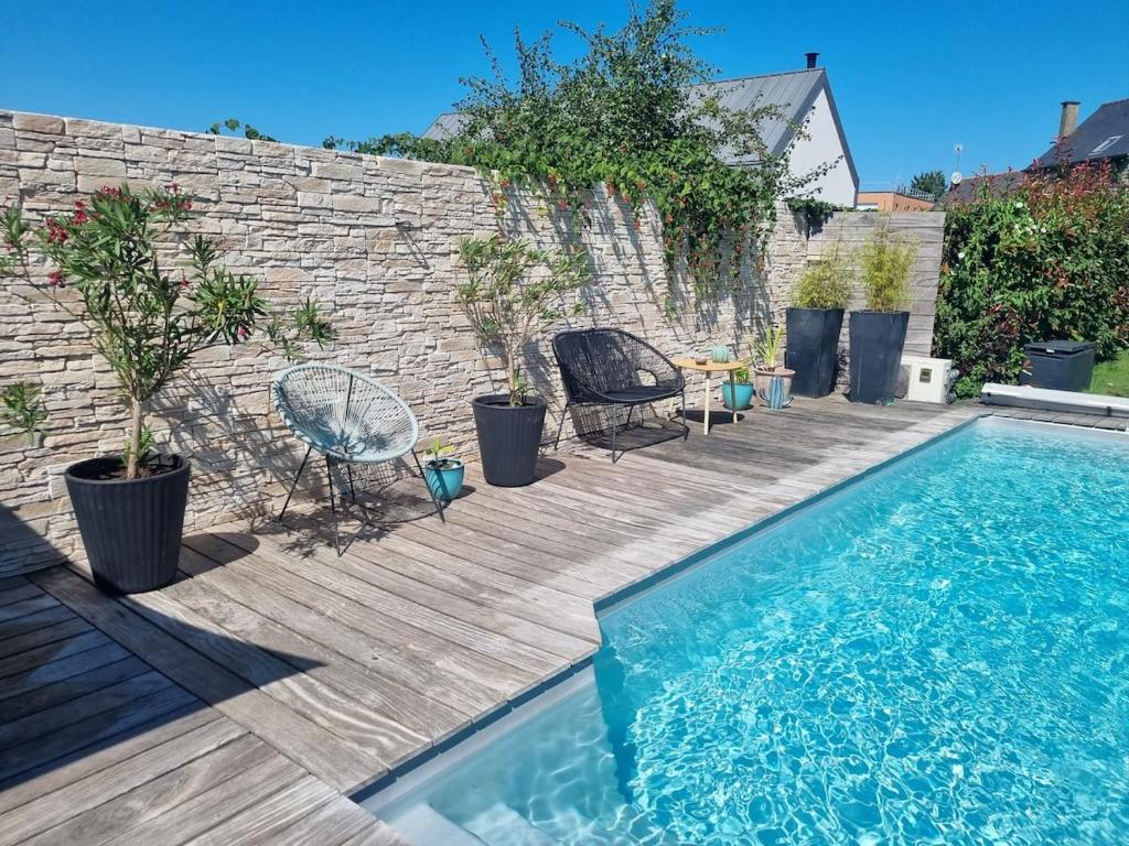 a swimming pool with chairs and a table next to a brick wall at Chez Audrey & Bastien in Dinan