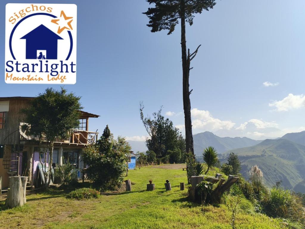 ein Haus auf einem Hügel mit einem Baum im Vordergrund in der Unterkunft Starlight Mountain Lodge SIGCHOS in Sigchos