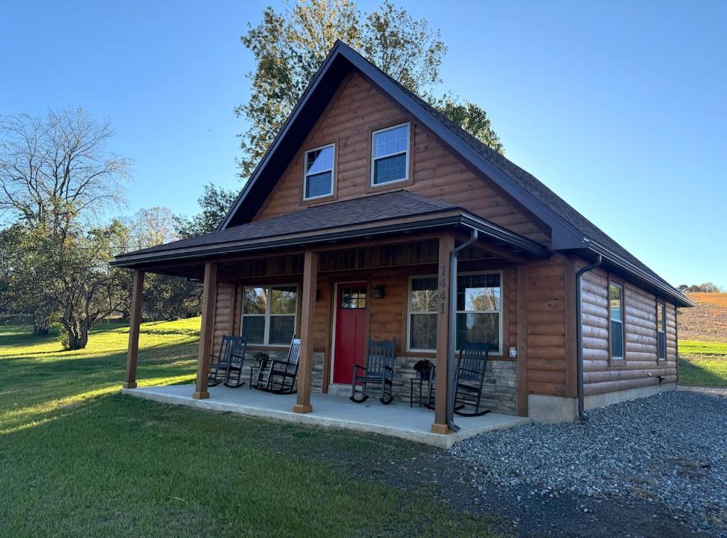 a log cabin with chairs and a red door at Cattail Cabin in Waterville