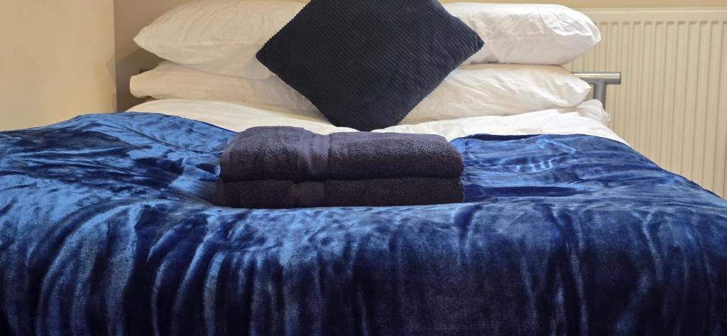 a blue blanket on top of a bed with pillows at Town Centre Studio with Ensuite in Aylesbury