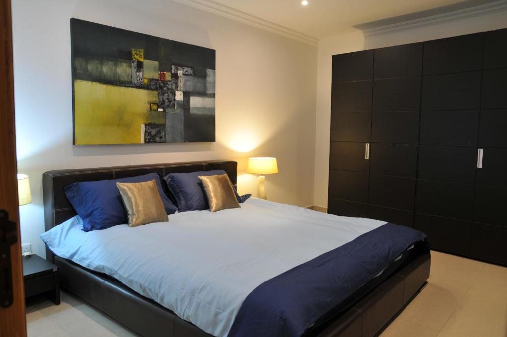 a bedroom with a large bed with blue and gold pillows at Luxury Apartment Marble Arch in St. Julianʼs