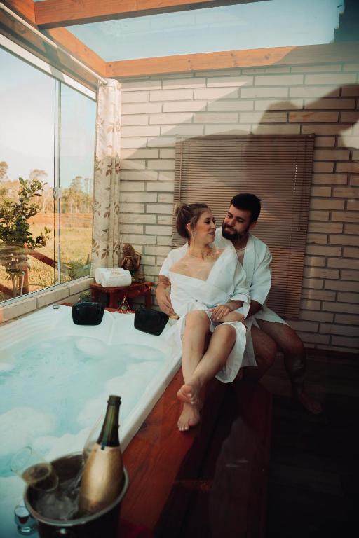 a bride and groom sitting next to a hot tub at Pousada Mirante dos Canyons in Praia Grande