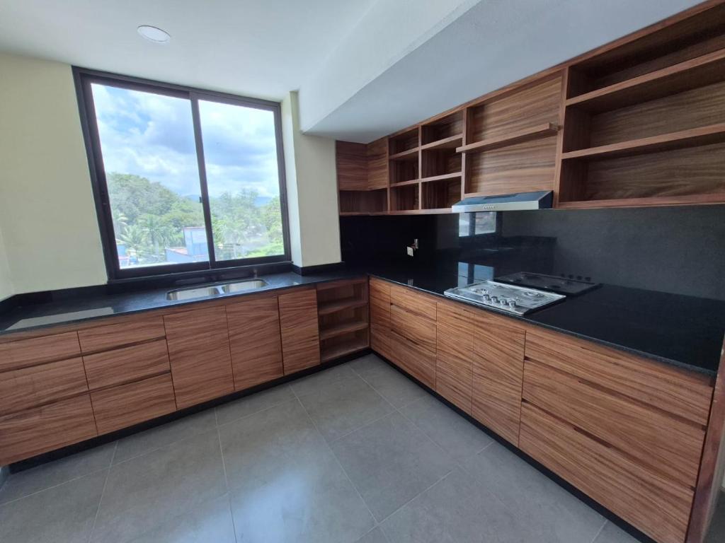 a large kitchen with wooden cabinets and a window at Departamento Huatulco 1 Torre Bel in Santa Cruz Huatulco