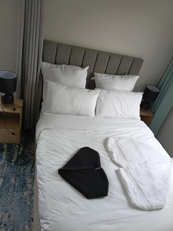a bed with a black hat and towels on it at Coastal Guest House with Free Parking and Braai Area in Cape Town