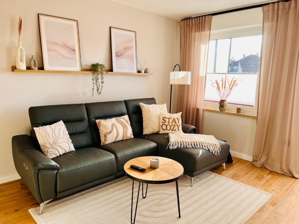 a living room with a black leather couch and a table at CozyHome mit Netflix, voll ausgestatteter Küche, Zentrums- und Bahnhofsnah, Balkon, self-Check-in möglich in Bückeburg