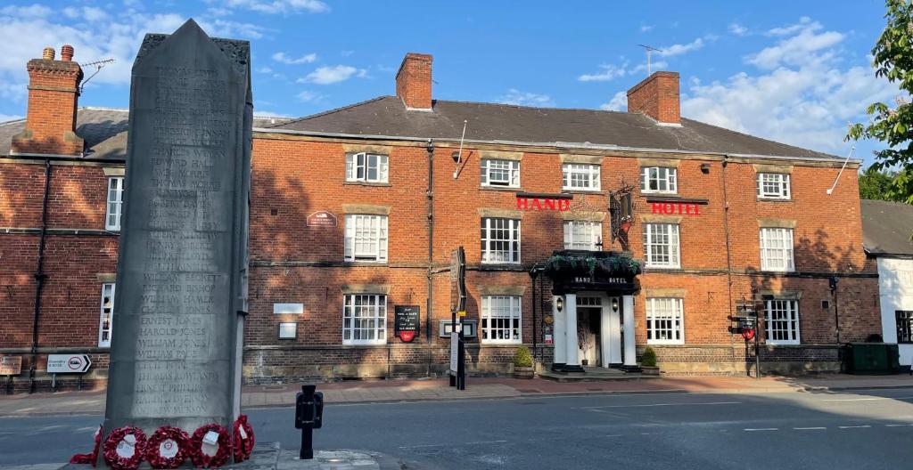 a large red brick building with a monument in front of it at The Hand Hotel in Chirk