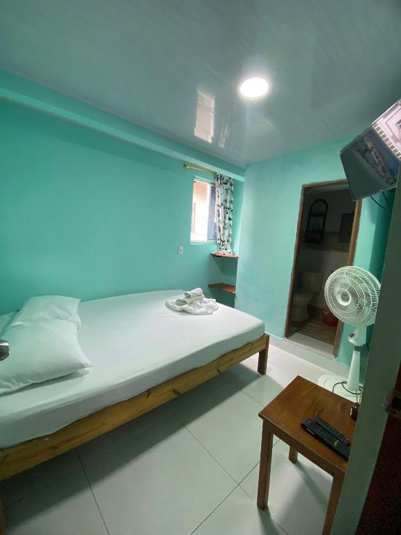 a bedroom with a bed and a table with a fan at Hotel Y Transporte LadyMar in Nuquí