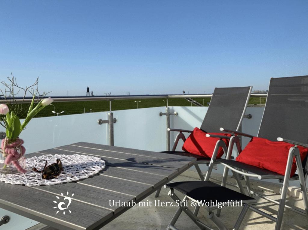 a patio table and chairs on a balcony with the view at Penthouse de Ool Blick auf das Wattenmeer in Neufeld