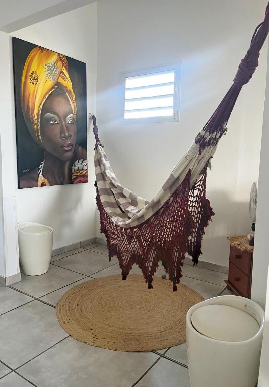 a hammock in a room with a painting on the wall at La maison de Vénus - Petite maison créole à 3 min du front de mer - proche de la plage de la Pointe Faula - kitesurf et activités nautiques in Le Vauclin