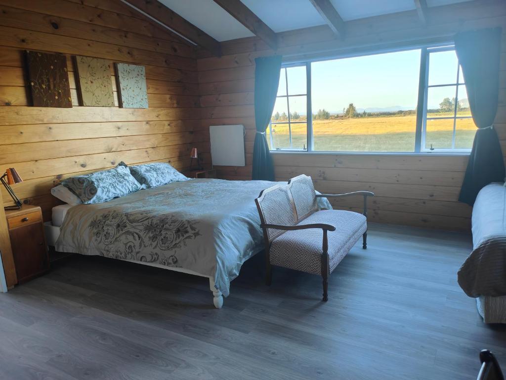a bedroom with a bed and a chair and a window at Riverside Loft in Turangi