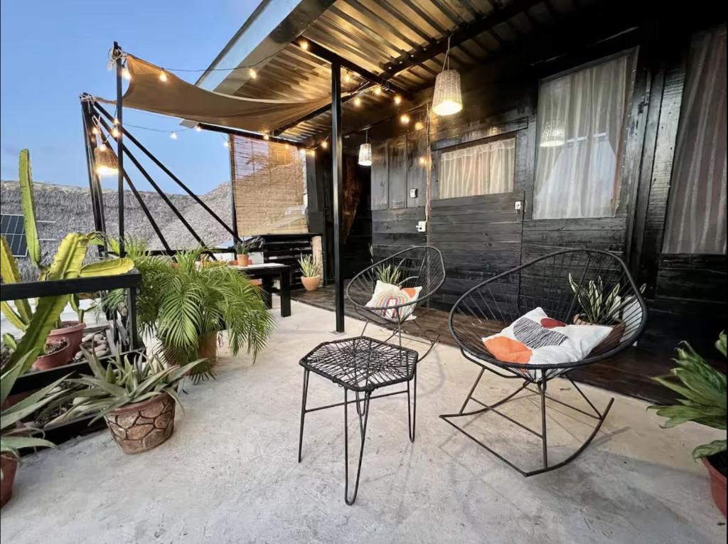 a patio with two chairs and tables and plants at Casa OMI in Brisas de Zicatela