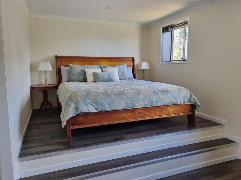 a bedroom with a bed with a wooden frame and a window at Gympie Townhouse in Gympie