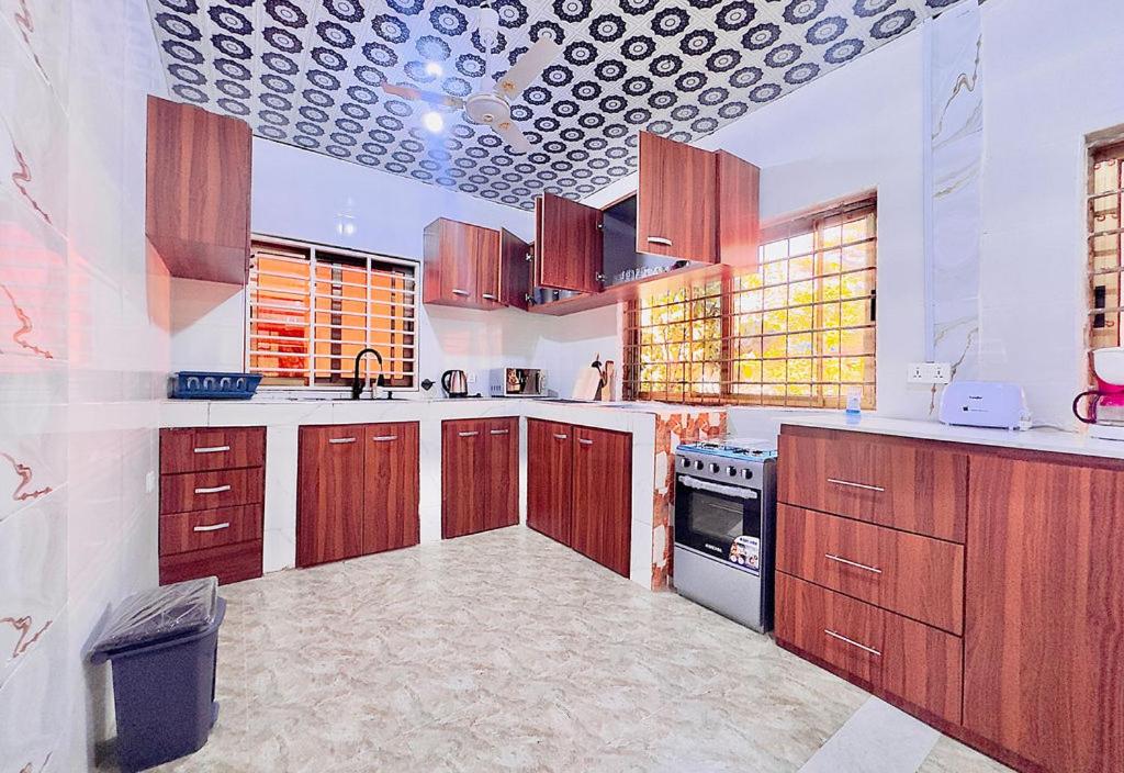 a large kitchen with wooden cabinets and a stove at Villa de chez nous in North Legon