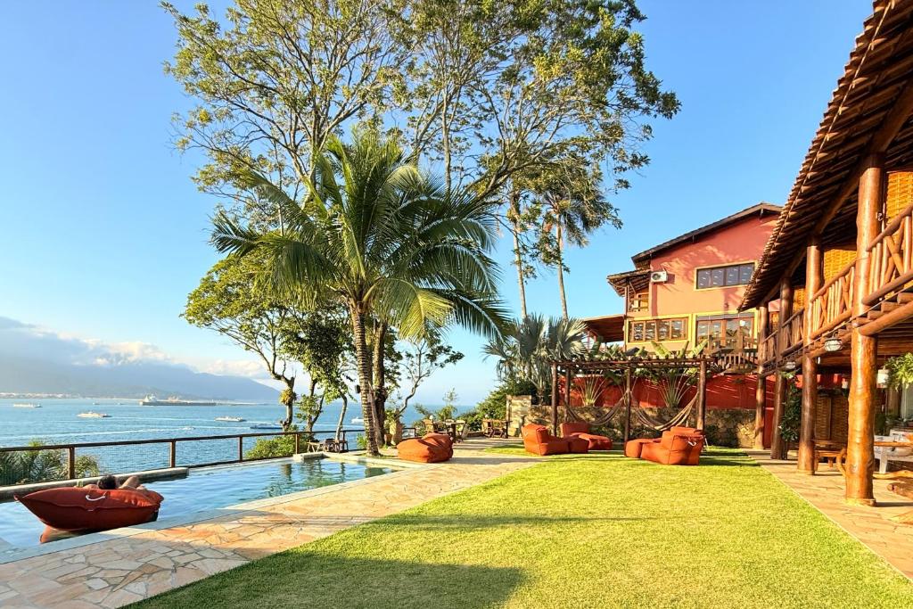 a resort with a swimming pool next to the ocean at Gidu Ilhabela in Ilhabela
