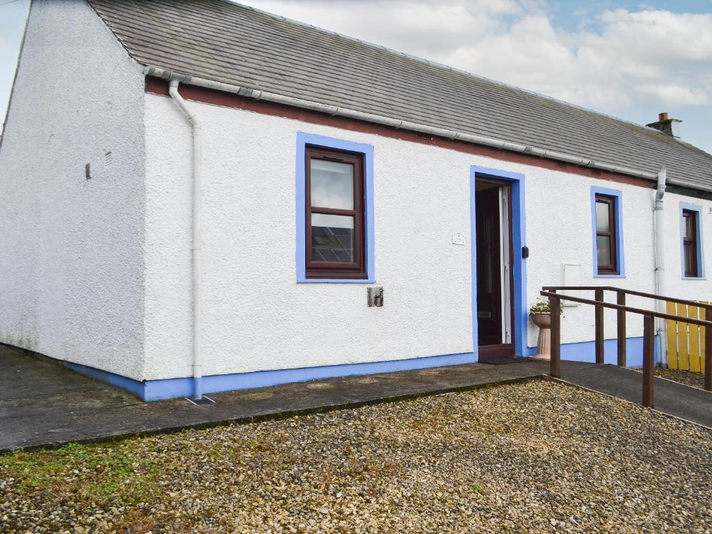 a white house with a blue door and a fence at Ashley Cottage in Bowmore