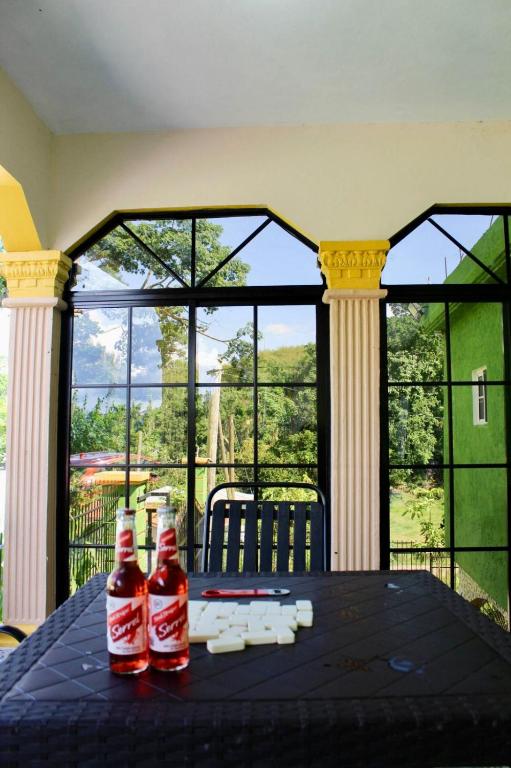two bottles of coke on a table in front of a window at Coke Guest House in Mandeville