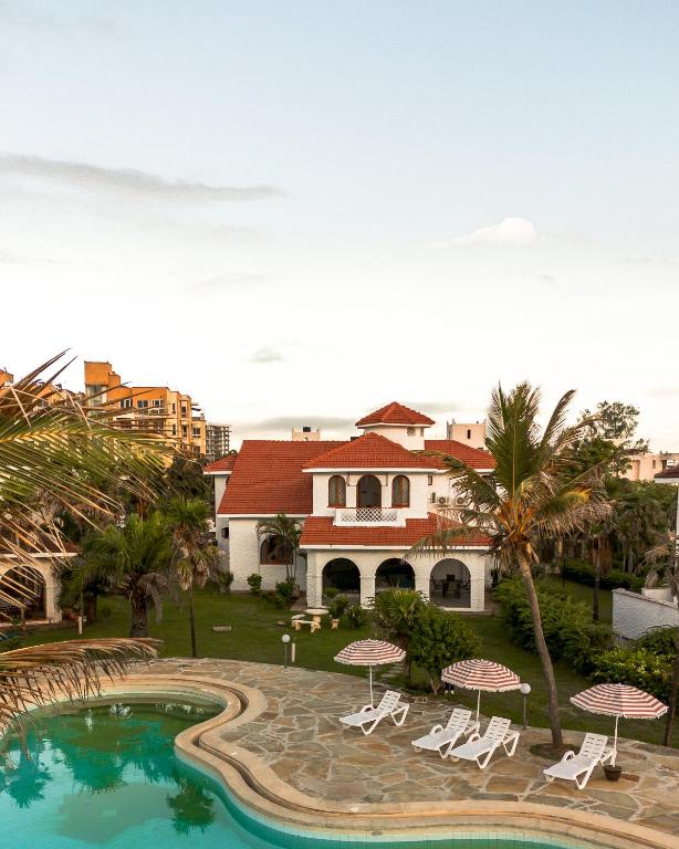 a resort with a swimming pool with chairs and umbrellas at Uttoru Creek Villa-2 in Mombasa