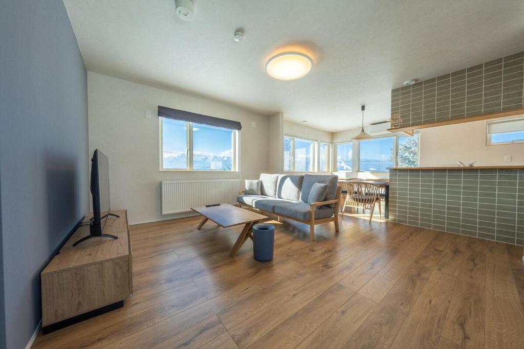 a living room with a couch and a tv at torinuma VILLA in Furano