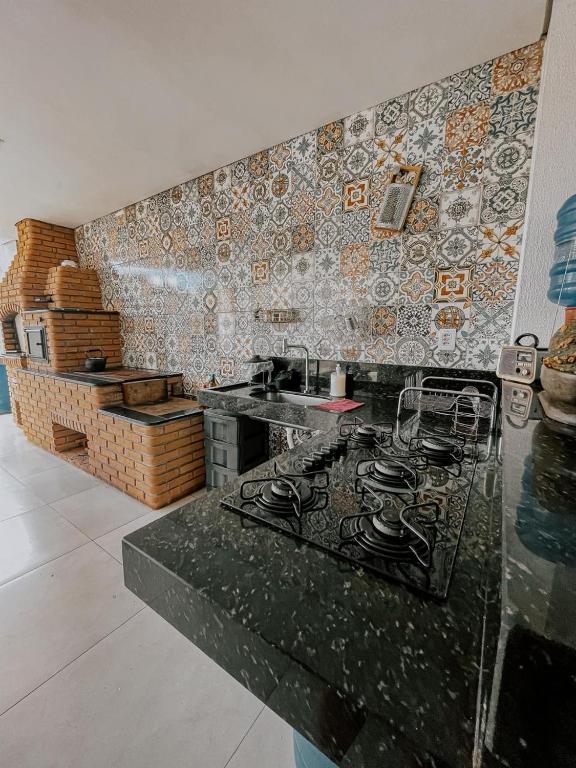 a kitchen with a counter with a stove and tiles at Suítes em casa ampla com área gourmet in Uberlândia