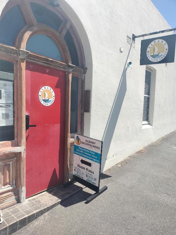 a sign in front of a building with a red door at Albany Bayview Lodge in Albany