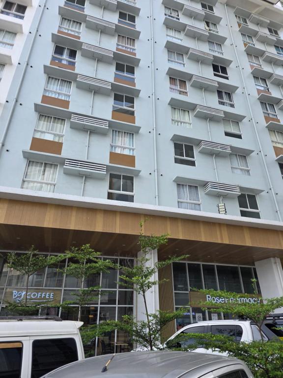 a tall white building with cars parked in front of it at Gem's Silid Tulugan in Cebu City