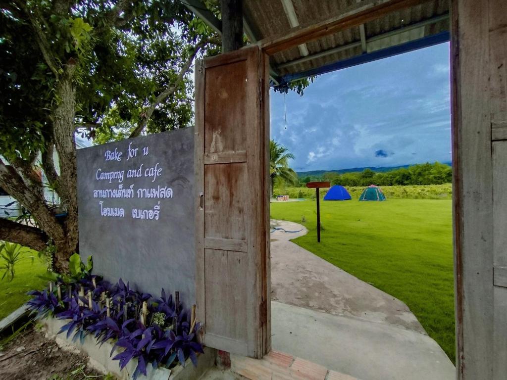 a door leading to a golf course with purple flowers at Bake for You Camping in Ban Nong Bua
