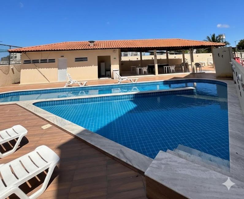 a swimming pool with two lounge chairs next to a building at Apartamento 2 Quartos com Piscina e Garagem in Maceió