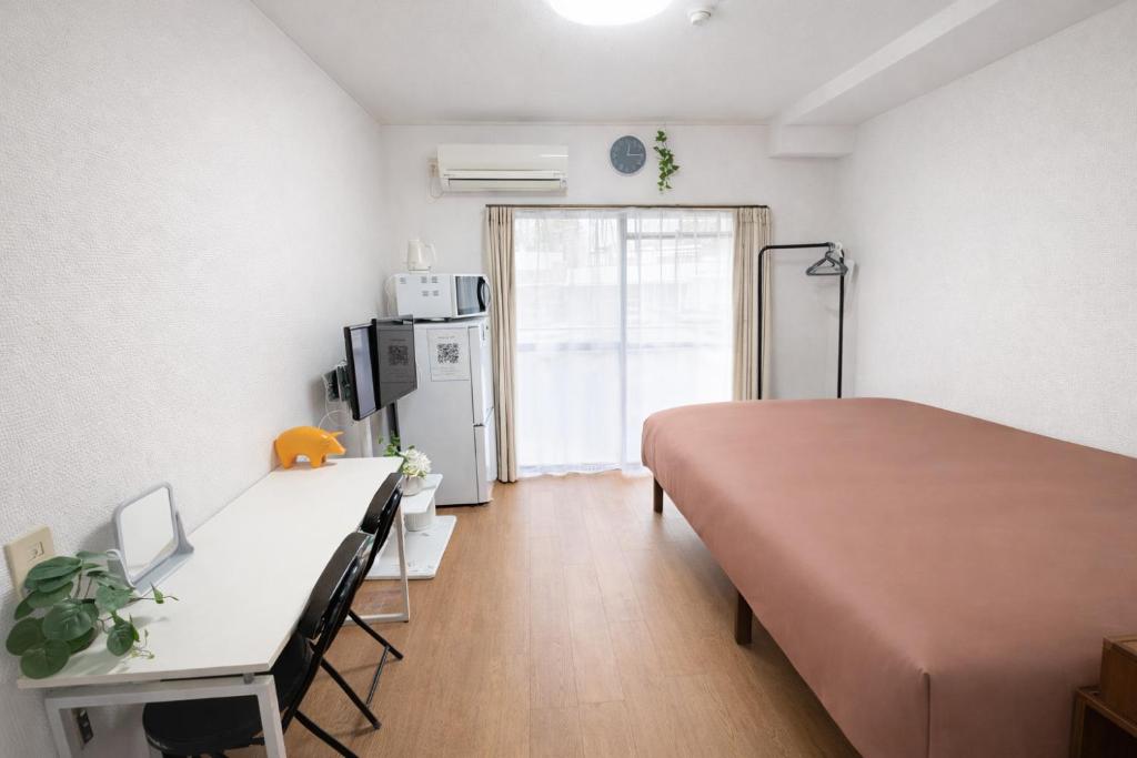 a bedroom with a bed and a desk and a refrigerator at ひまわり in Dazaifu