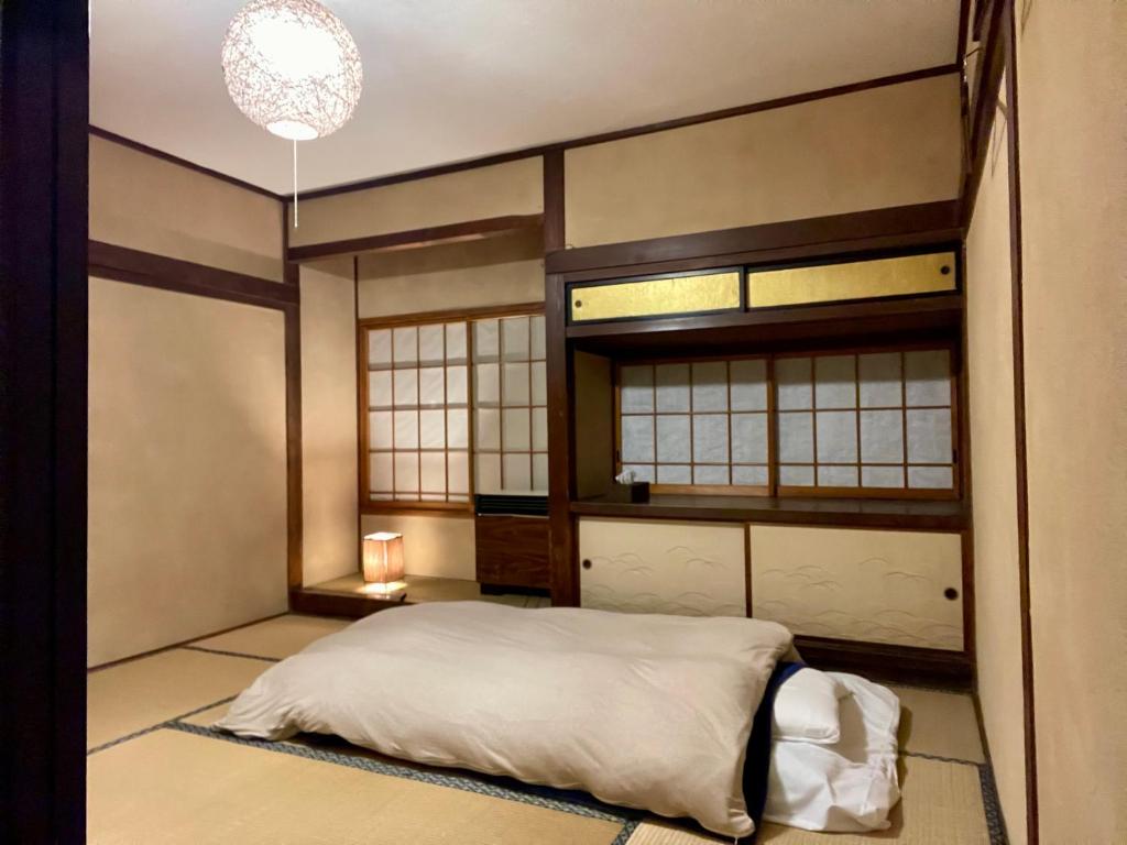 a bedroom with a bed in a room with windows at 北アルプス麓のゲストハウス林屋 in Omachi