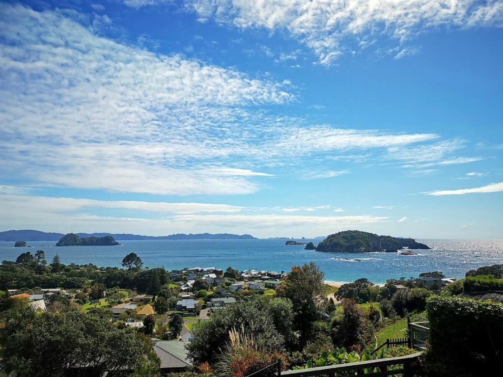 a view of a town and the ocean with islands at Hahei Island Views in Hahei