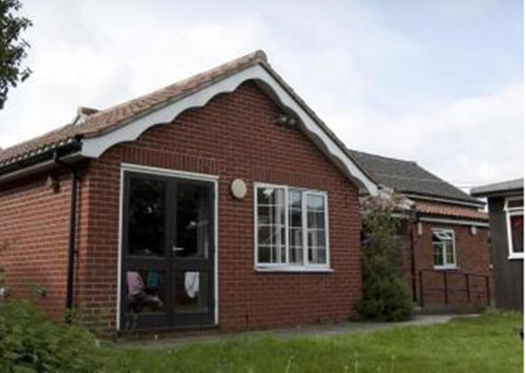 a red brick house with a large window at YHA Blaxhall in Blaxhall