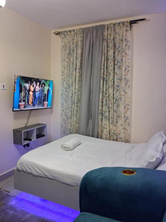 a bedroom with a bed with a tv on the wall at BoniMark in Machakos
