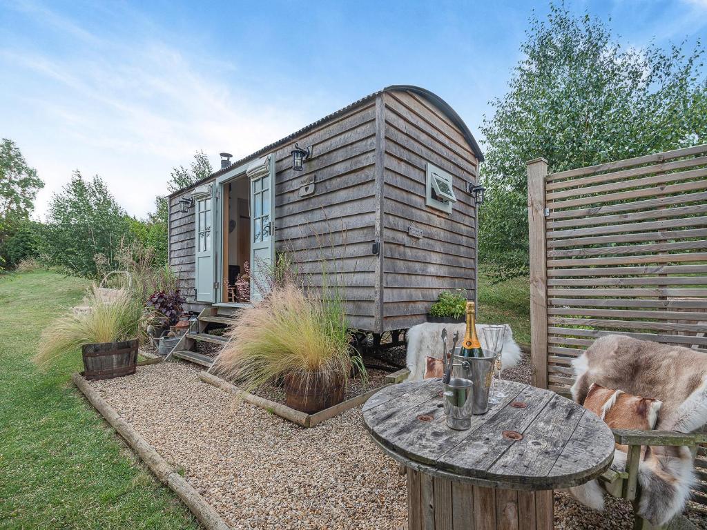 a small cabin with a table in the yard at Herbie's Shepherd Hut - Uk50229 in Nottingham