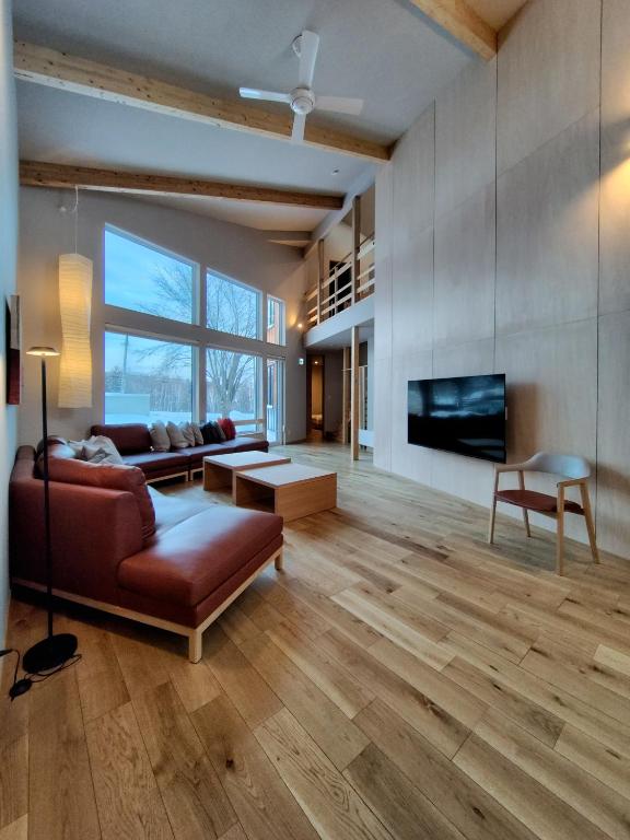 a living room with a couch and a tv at Yama Sakura in Furano