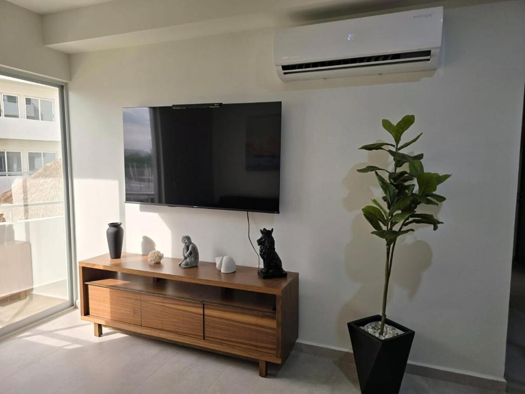 a living room with a tv and a potted plant at Bluu lagoons in Los Cerritos