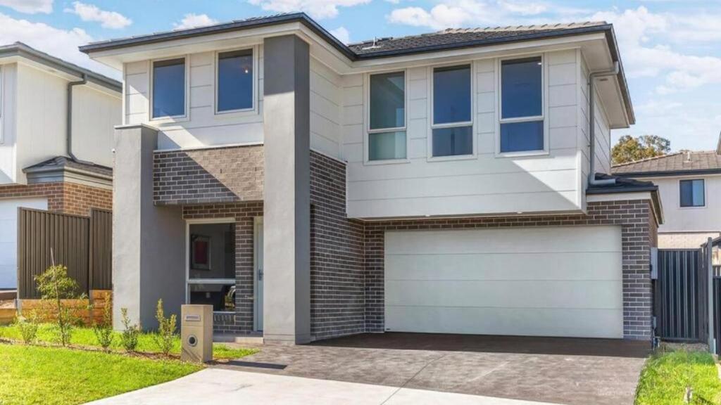 a large white house with a garage at Little Gem in Northwest! in Riverstone