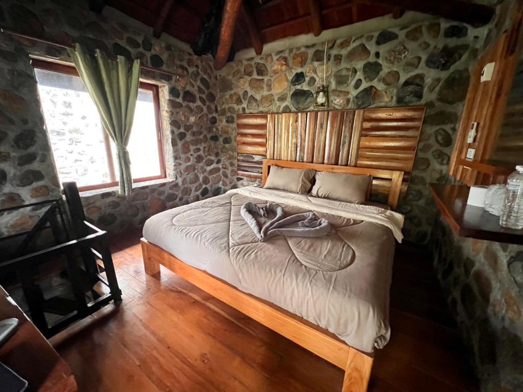 a bedroom with a bed in a room with stone walls at บ้านชนเผ่าแคมปิ้งแอนด์รีสอร์ท in Pang Mapha