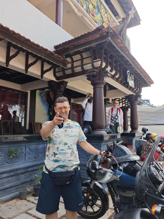 a man standing next to a motorcycle looking at his cell phone at Relax inn cherai beach in Cochin