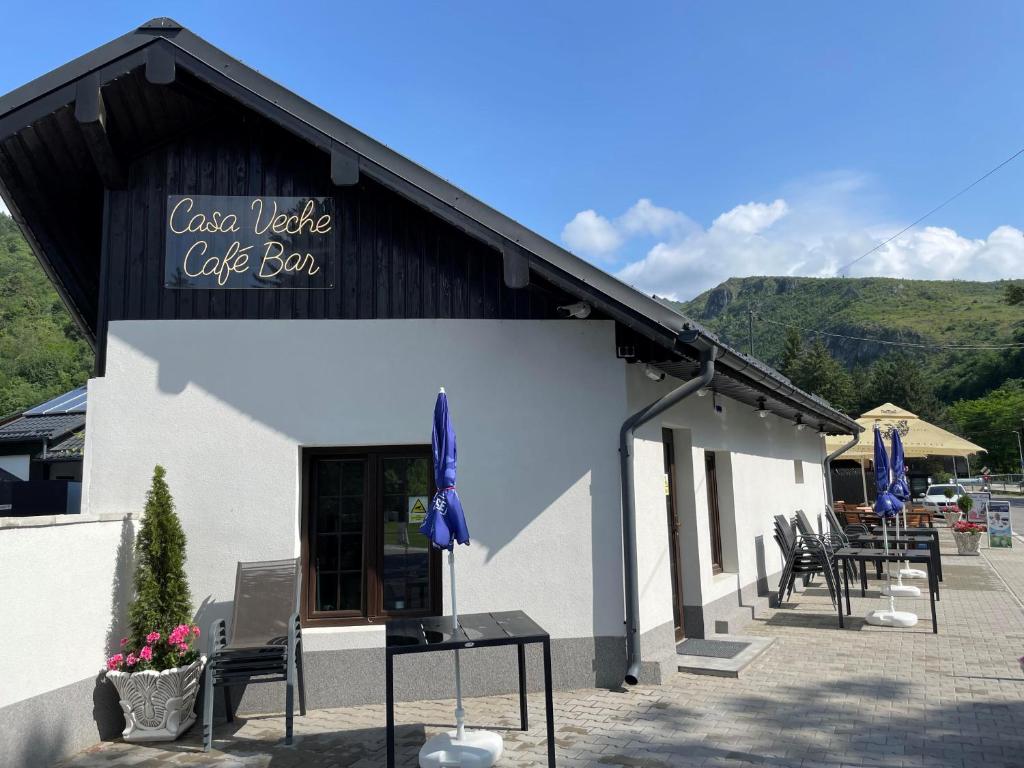 a building with a cafe with chairs and blue umbrellas at Casa Veche in Runcu