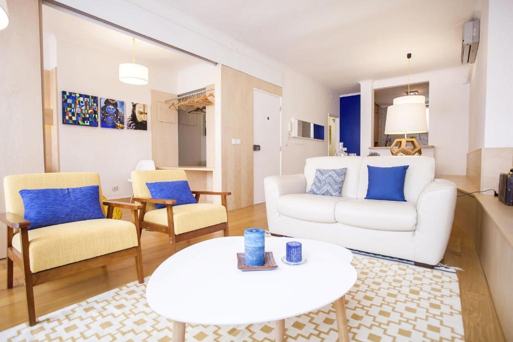 uma sala de estar com um sofá branco e cadeiras em Carmo in Chiado Apartment em Lisboa