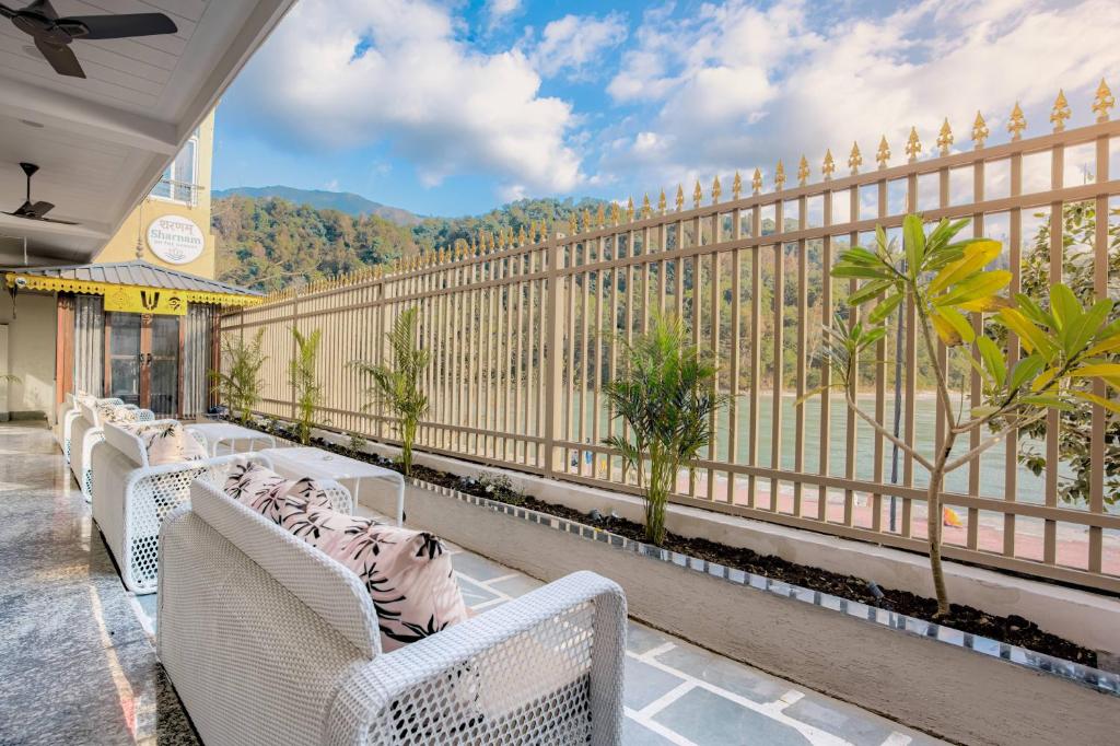 a balcony with white wicker chairs and a fence at Sharnam On The Ganges in Rishīkesh