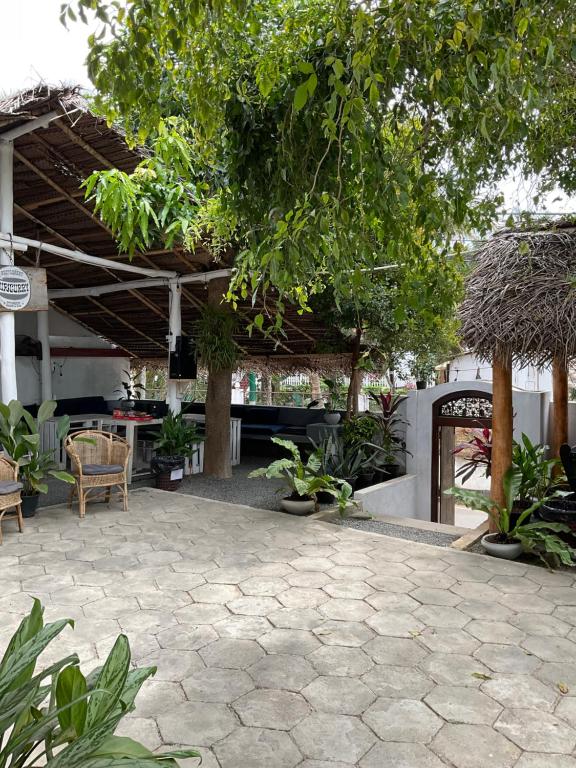 a patio with a table and chairs and trees at Hiricurry,Rooms Hostel & Restaurant in Dickwella