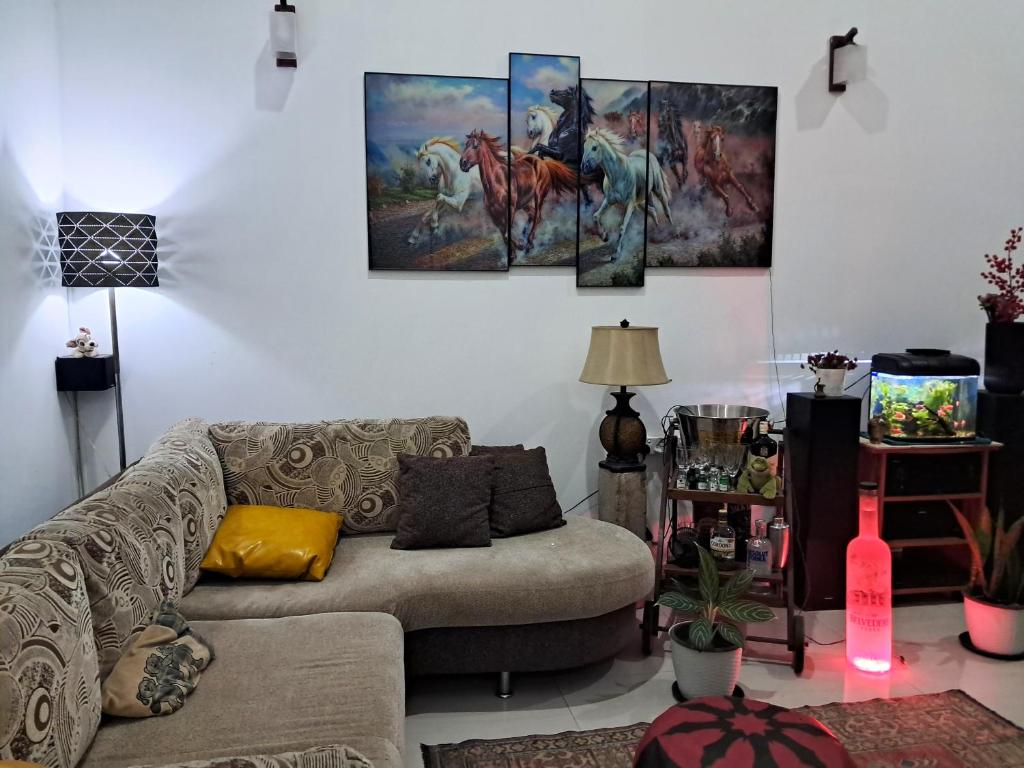 a living room with a couch and paintings on the wall at Vibes Home Stay in Athurugiriya